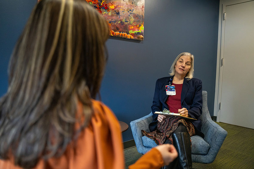 A woman sitting in a chair listening to a person talk.